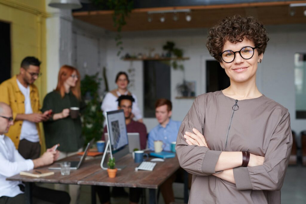 A sales professional standing with her team behind her.